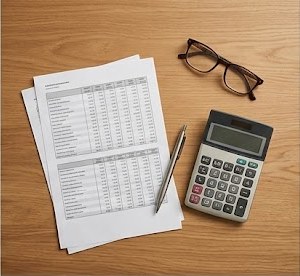Printed homeschool transcript with calculator and pen on desk